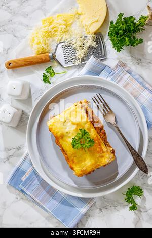 Lasagne mit Hackfleisch prepared in popular German style with layered ground beef and melted cheese served on a grey plate on a marble background Stock Photo