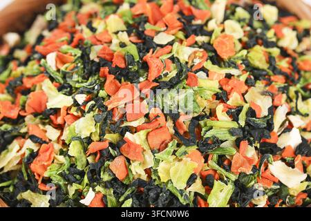 Close-up of mixed dried vegetable flakes piled together in a wooden bowl. Stock Photo