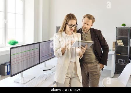 Business colleagues analyzing financial data on tablet in bright modern office Stock Photo