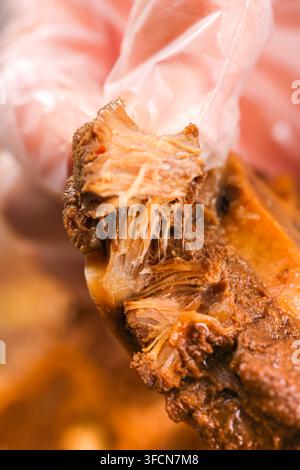 Close-up of shredded braised meat held in a gloved hand against a blurred background. Stock Photo