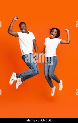 Emotional black couple holding hands and jumping up Stock Photo