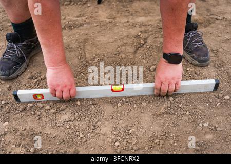 construction worker using spirit level on site on the ground during work, close up, real Stock Photo
