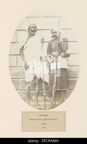Portrait of two unknown men from Awadh, Uttar Pradesh, India, photograph, page, inscription: 'TEEHURS., SUPPOSED ABORIGINAL., OLD.', number: '(85)', c. 1858 - in or before 1868, photographer, North India, paper, albumen print, height 195 mm x width 140 mm, human races, peoples, nationalities., Two men standing side by side in front of a paneled wall are shown inside an oval frame; the man on the left is wearing a light draped garment, is barefoot, and holds a long thin staff, while the man on the right wears darker, layered clothing with a patterned lower garment, a headwrap, multiple necklace Stock Photo