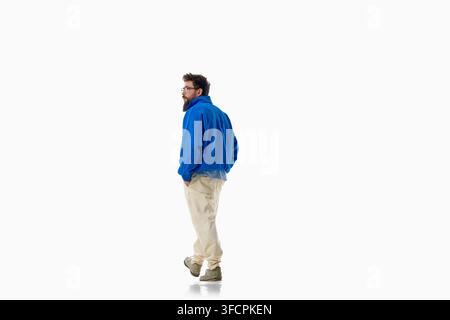 Fashionable man stands in bright blue sweater and relaxed cream pants Stock Photo