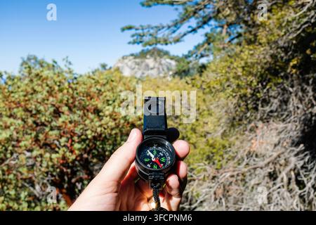 Hand holding a compass while hiking outdoors Stock Photo