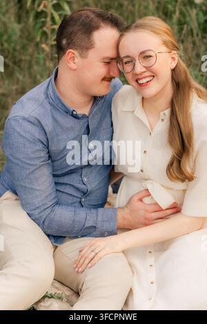 Happy expecting couple sit together in a field Stock Photo