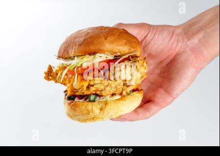 A person's hand holding a loaded crispy chicken sandwich Stock Photo