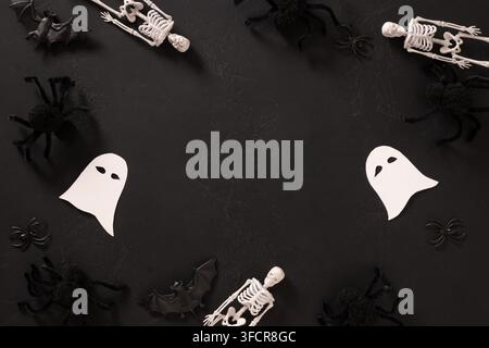 Halloween frame made of ghosts, skeletons, spiders and bats on textured black background with large copy space for seasonal design. Stock Photo