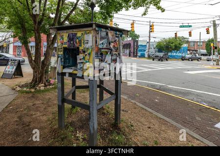 A weathered community bulletin board covered in posters and flyers stands on a street corner in the NoDa arts district, Charlotte, North Carolina, USA Stock Photo