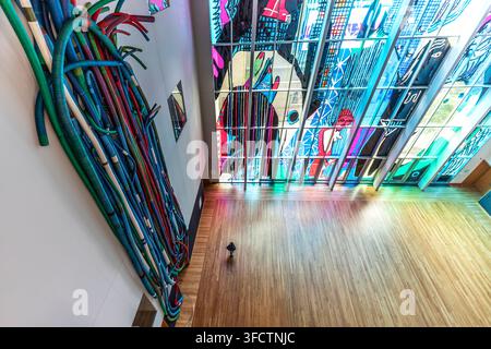Overhead view of a colorful hanging sculpture and a tall graphic stained glass window inside Mint Museum Uptown, Charlotte, North Carolina, USA Stock Photo
