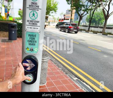Pedestrian push-button uniton a traffic light pole on, featuring a contactless sensor area with a glowing hand icon and an arrow indicator, Singapore Stock Photo