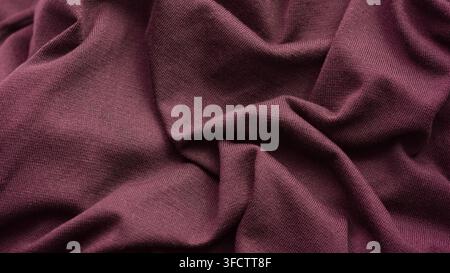 A close-up shot of a crumpled and soft maroon knitted fabric texture Stock Photo