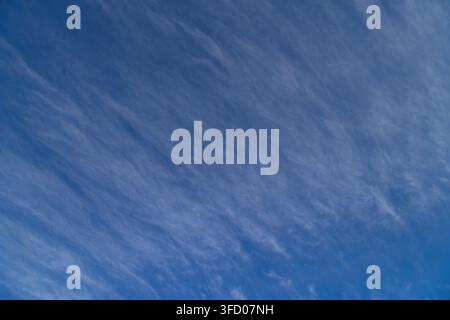 Dynamic view of bright blue sky filled with delicate, wind-swept cirrus clouds. Thin, feathery formations create an abstract pattern against the deep Stock Photo