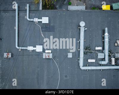 Aerial view of a flat rooftop with metallic ventilation ducts and pipes on a wet surface during a rainy day in Riga, Latvia. Stock Photo