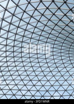 A modern glass dome roof featuring a repeating geometric steel grid and skylight panels, creating airy, minimalist interior with rhythmic patterns Stock Photo