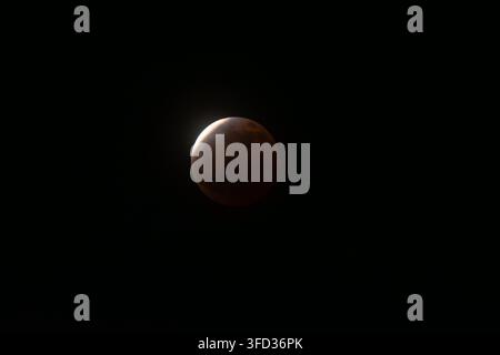 Partially eclipsed moon glows with a reddish hue against the vast darkness of space, presenting an awe-inspiring astronomical event and natural wonder Stock Photo