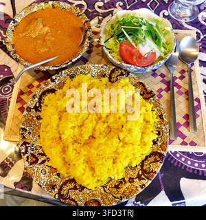 Delicious Sri Lankan cuisine set meal featuring aromatic yellow rice, flavorful curry, and fresh green salad served on patterned plates. Stock Photo