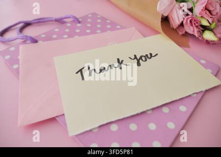 Thank you card with gift bag and flowers on table Stock Photo