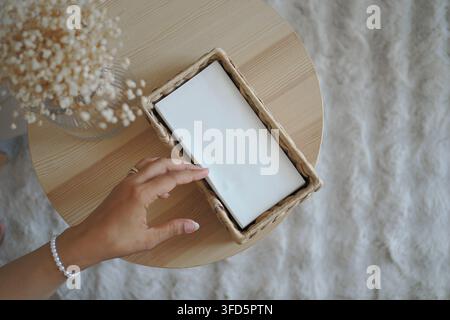 Women’s hand reaching for a tissue in a box on a wooden table Stock Photo