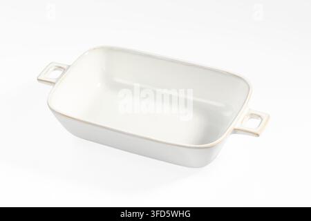 Minimalist white ceramic baking dish with rounded corners small side handles, shot against seamless white background. Soft lighting highlights smooth Stock Photo