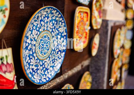 A vibrant selection of traditional hand-painted ceramic plates displayed on a dark wooden wall. Stock Photo