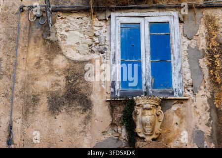 A rustic wooden window frame on a distressed building facade in Italy. Stock Photo