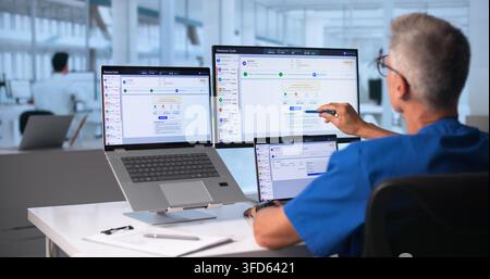 Healthcare Manager Carefully Reviews Medical Billing Codes Using Laptop Computer. Stock Photo