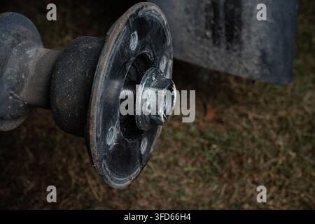 Close-up of a loosened wheel hub nut on the threaded axle during trailer wheel bearing maintenance and disassembly, with copy space. Stock Photo