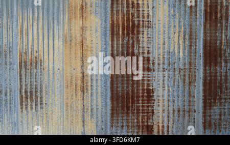 Closer view of weathered blue tinted corrugated galvanized metal surface showing variegated blue, yellow, orange and burgundy rust colors Stock Photo
