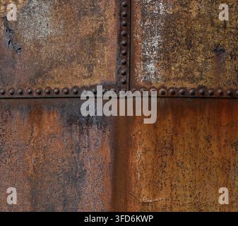 Close up of rusty galvanized metal water tank surface with flaking corrosion, pitted metal and rust holes on weathered panels Stock Photo