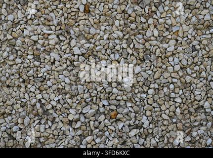 Closer view of decorative crushed stone aggregate wall surface showing embedded angular stone pieces with varied gray, tan, black Stock Photo