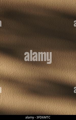 A minimalist vertical composition featuring soft sunlight shadows cast across a rough brown plaster wall texture, creating a serene and aesthetic back Stock Photo