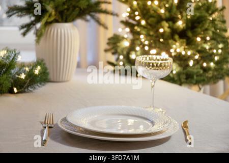 Elegant Christmas table setting with glowing tree lights Stock Photo