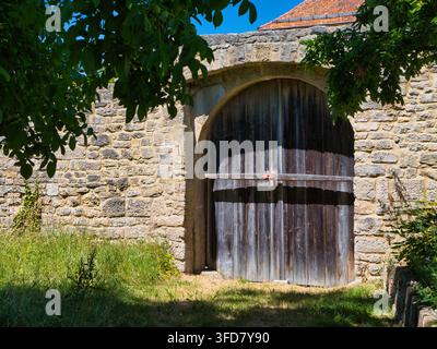 Rothenburg, Germany - Jul 03 2026: Weathered wooden gate set in a stone arch in Rothenburg Germany framed by leafy trees and summer sunlight Stock Photo