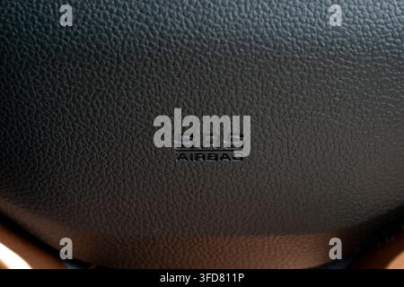 Embossed SRS Airbag safety label on the textured black leather central hub of a modern car steering wheel. Stock Photo