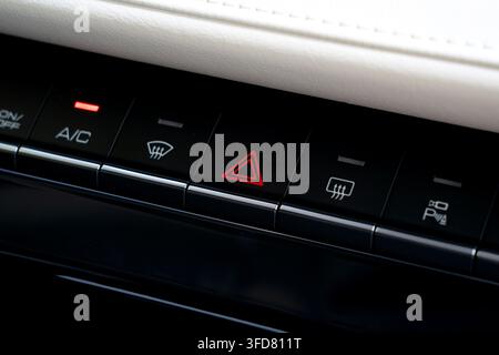 Sleek car dashboard control panel featuring illuminated hazard warning lights symbol, air conditioning buttons, and defroster switches Stock Photo