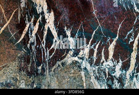 Closeup of polished marble with brown, teal, white, and cream mineral veins forming an intricate natural stone texture. Stock Photo