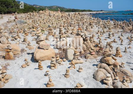 Numerous balanced stone cairns on a sandy beach under bright daylight. Berchida beach - Sardinia - Italy Stock Photo