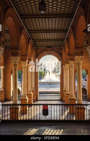 Framed view of Plaza de Espana Public Square in Seville, Spain, showing arched gallery, central fountain, brick arcade, and marble column Stock Photo
