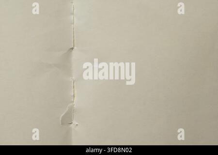 Distressed cream paper background showing vintage texture with folded seam and damage Stock Photo