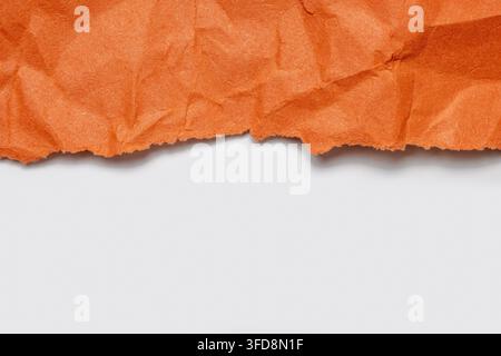 Orange crumpled paper with a ripped edge is contrasting with white background copy space Stock Photo
