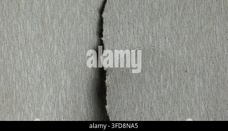 Gray cardboard texture showing a rough tear and separation down the middle Stock Photo