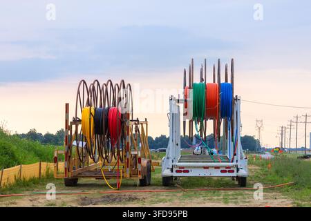Colorful conduit cables on trailers used for underground utility installation at a construction site Stock Photo