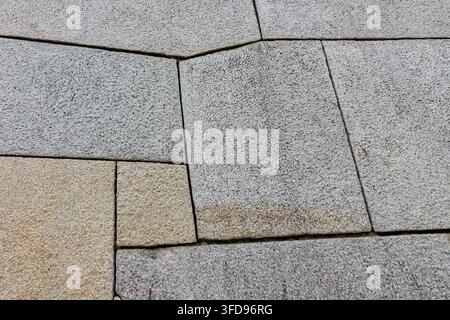 A meticulously crafted paving surface featuring a staggered, geometric arrangement of natural stone slabs in a range of shapes and textures Stock Photo