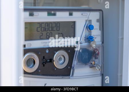 Close-up view of a modern digital electricity meter with a clear display showing usage data and keys inserted for access Stock Photo