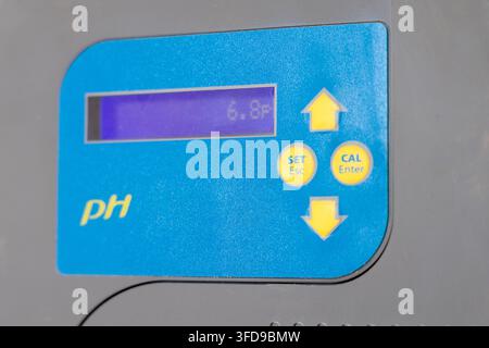 Close-up of a blue and gray digital pH meter with a purple LCD screen displaying a reading and control buttons for calibration and settings Stock Photo