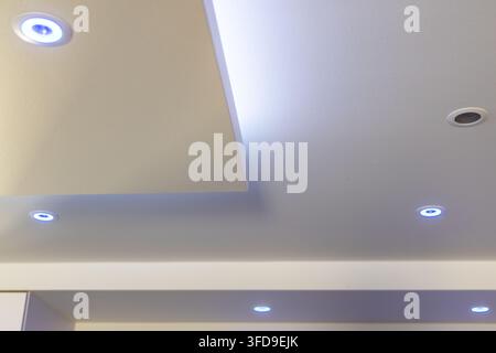 Recessed ceiling lights with a contemporary design, featuring soft blue LED illumination for a sophisticated atmosphere Stock Photo