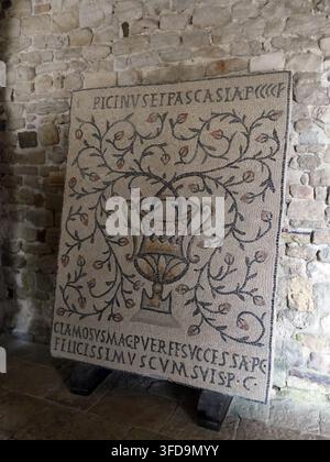 POREC, CROATIA - OCT 2, 2024 - Mosaic with floral vase and latin inscriptions. Displayed on a stand against a stone wall. , Euphrasian Basilica, Churc Stock Photo