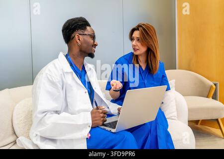 Diverse medical team collaborating on healthcare data using laptop Stock Photo