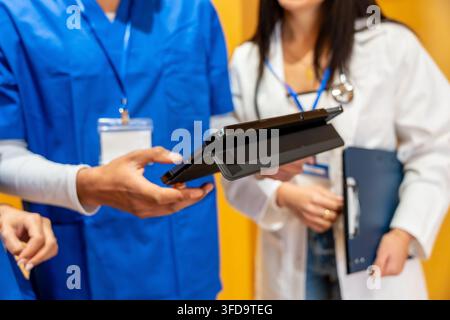 Medical team collaborating and discussing patient data using tablet Stock Photo